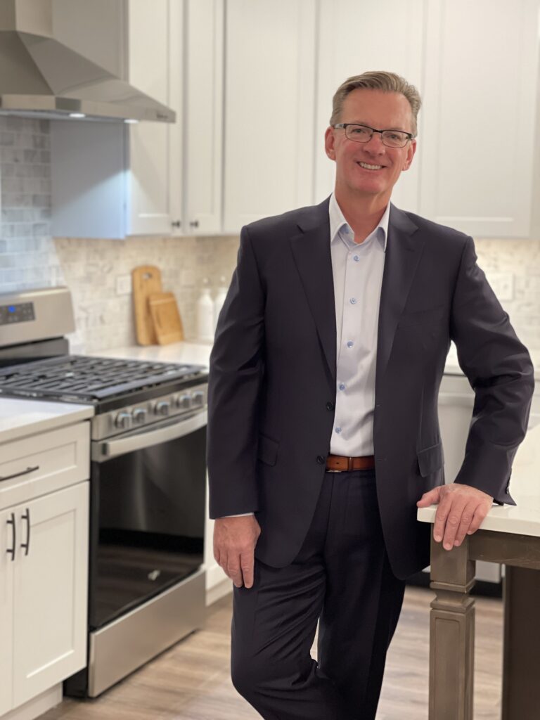 Man in a suit standing in a well-furnished kitchen