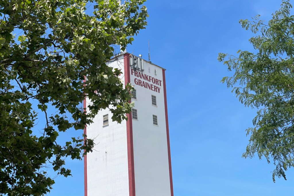 A red and white clock tower next to a tree.