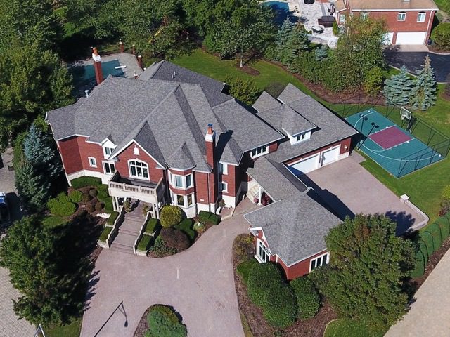 An aerial view of a large home with a tennis court.