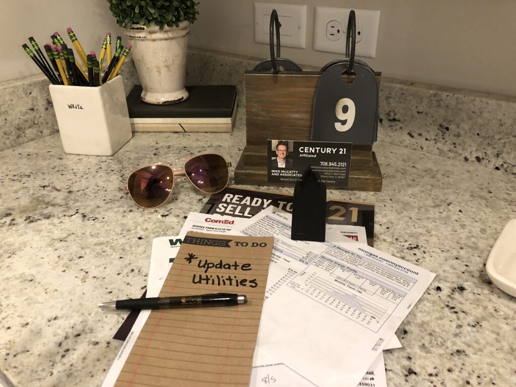 A kitchen counter with a notebook, pen, and sunglasses.